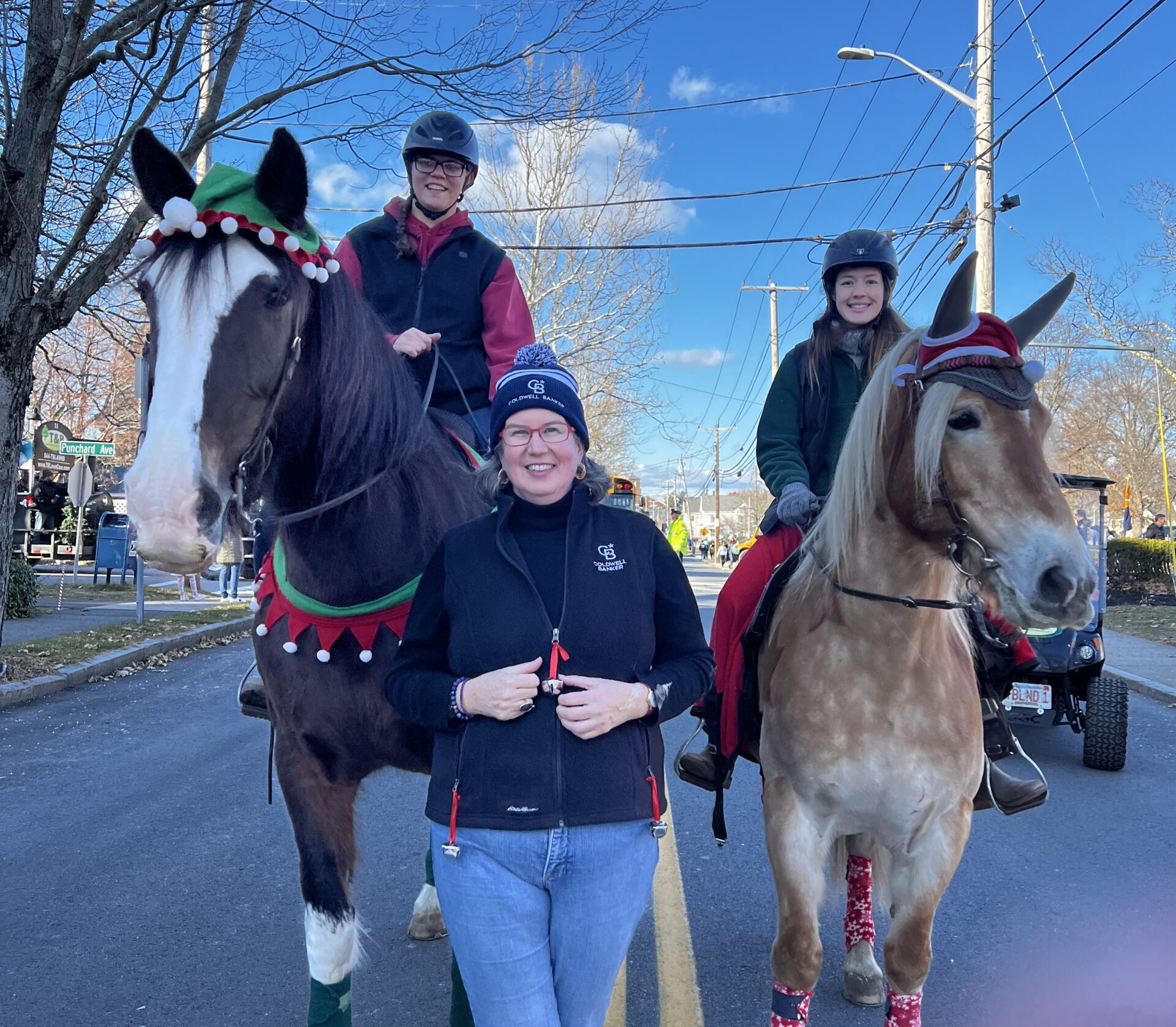 Rider Jenn stands smiling between two Ironstone Farm horses during a holiday parade